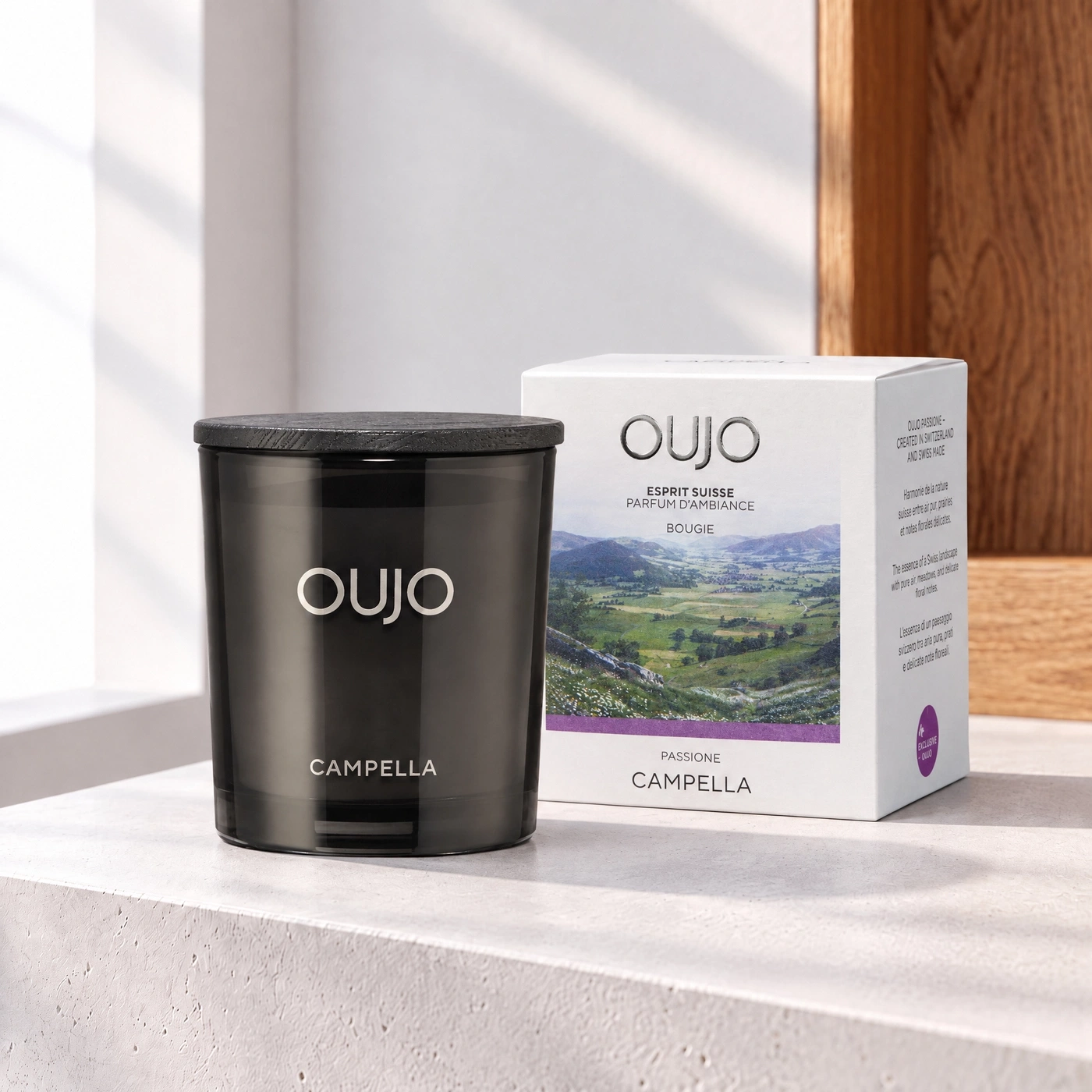 A candle with a gift box featuring a landscape image.