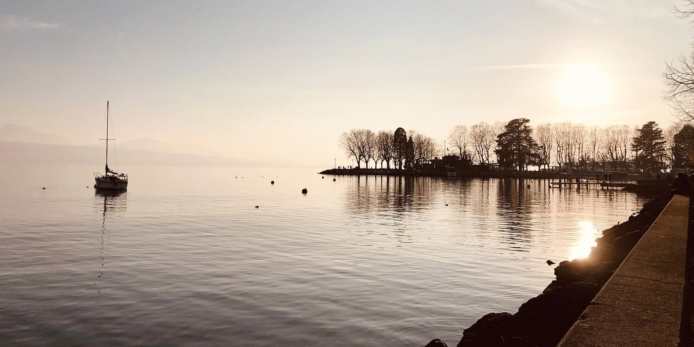 Sailboat on a lake at sunset with trees on the shore