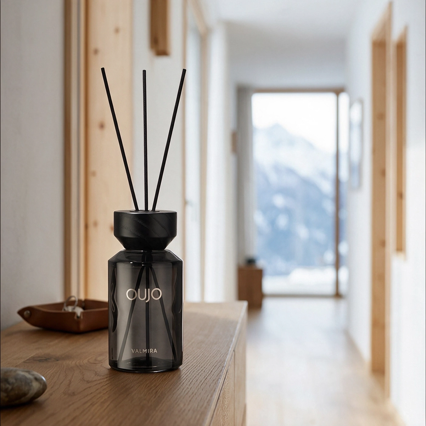A diffuser with scent sticks sits on a wooden table.