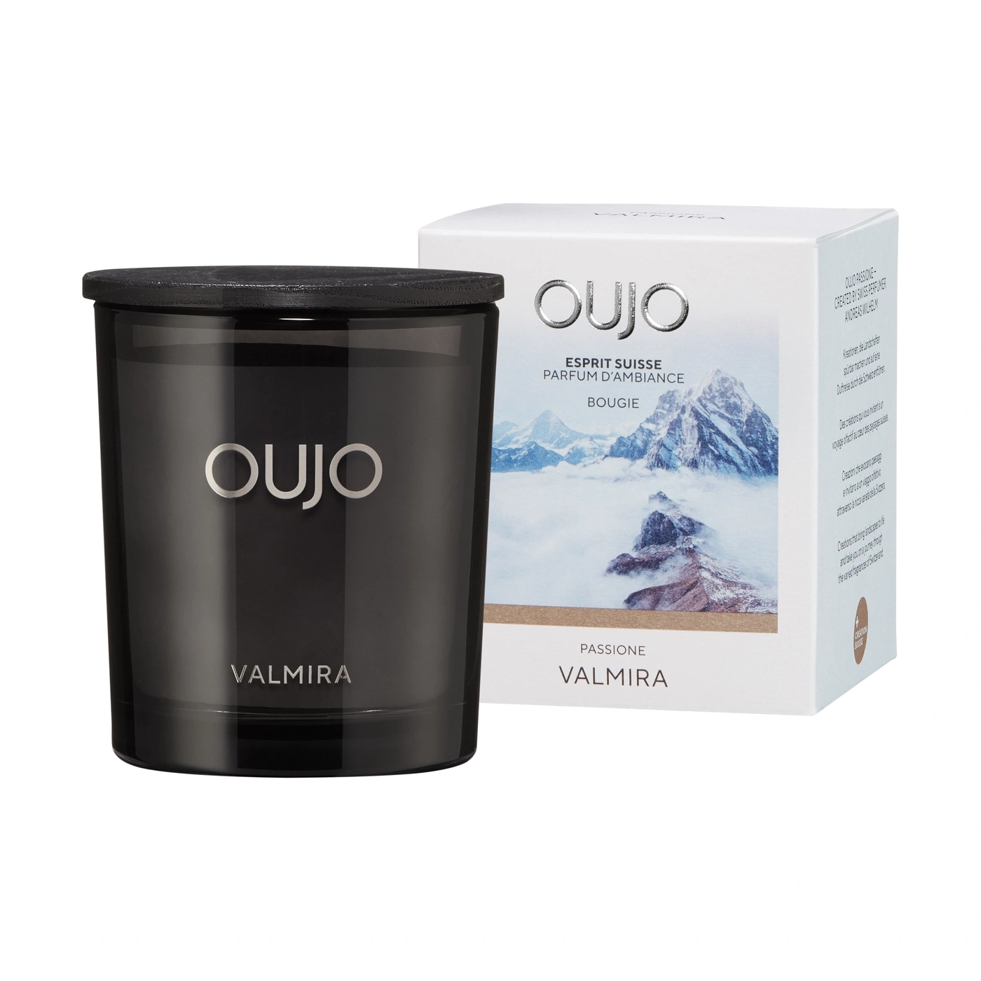 Candle in a glass next to its box with a mountain scene