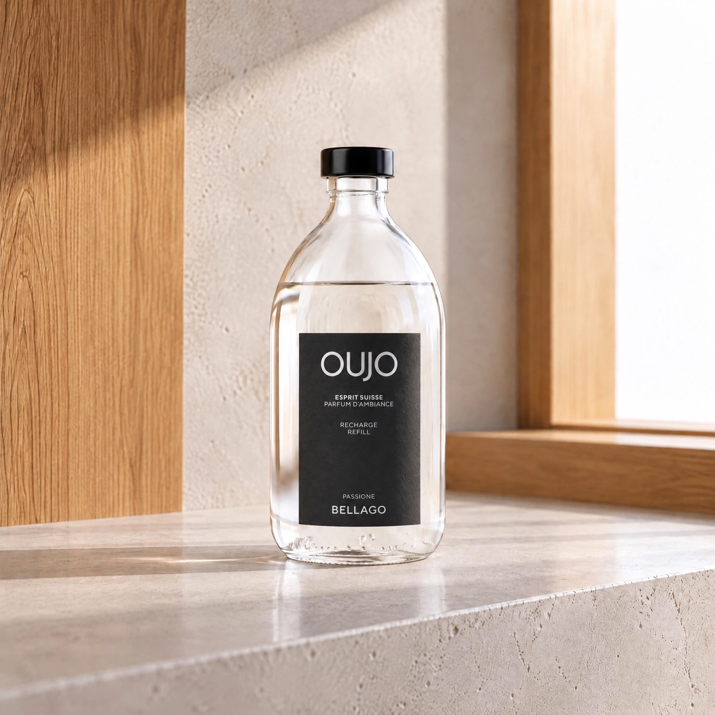 A glass bottle with scented refill oil sits on a stone ledge, illuminated by sunlight.