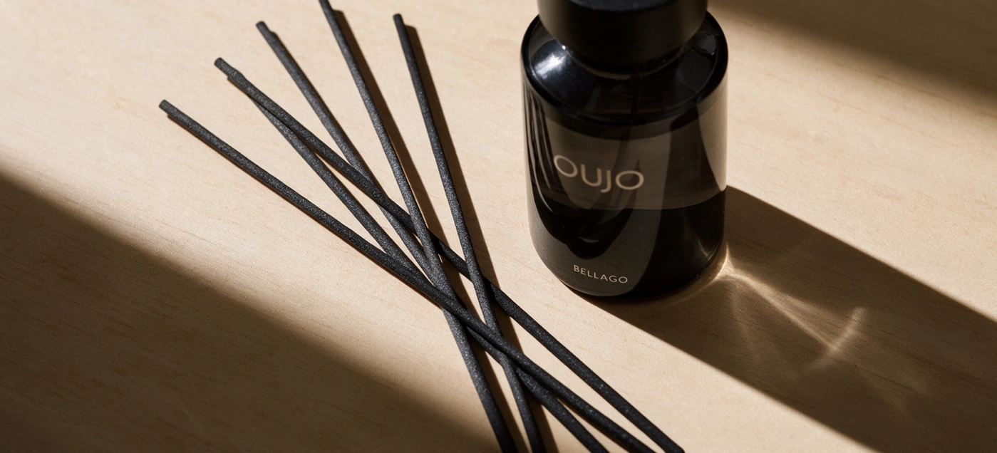 A black diffuser with reeds on light wood.