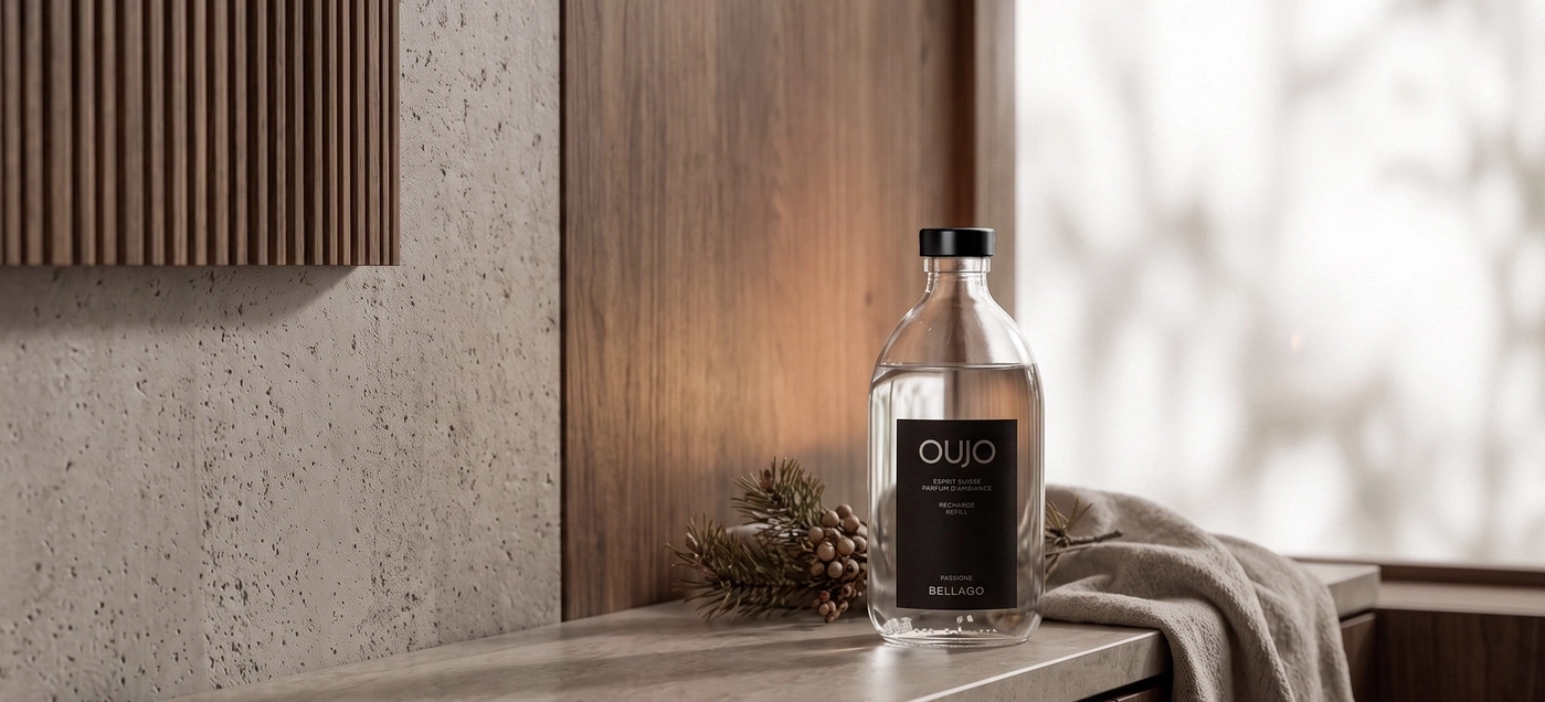 A bottle of perfume on a table with branches and fabric.