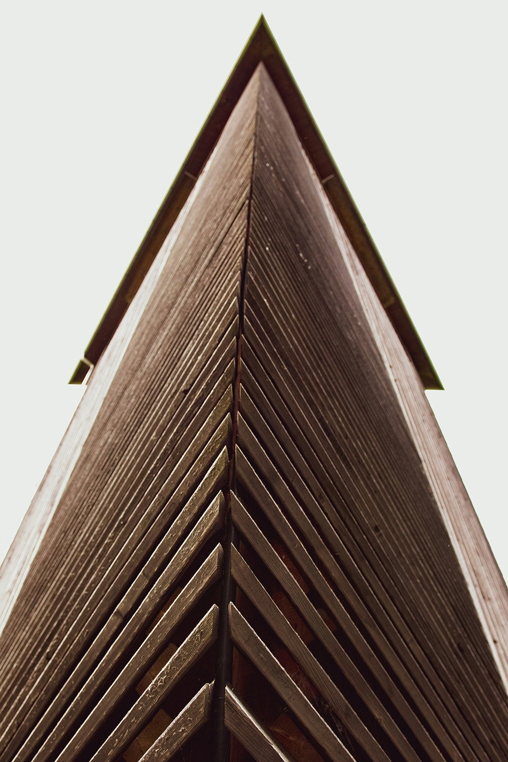 Wooden facade of a pointed building, seen from below.
