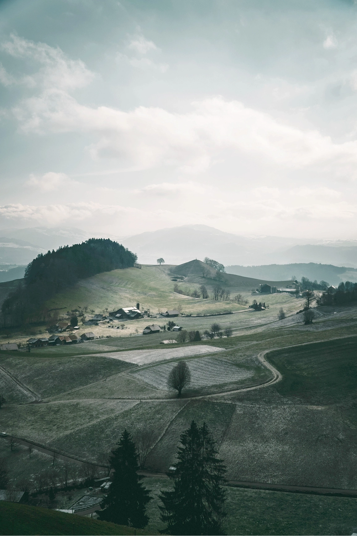 Rural hilly landscape with farms and fields in winter