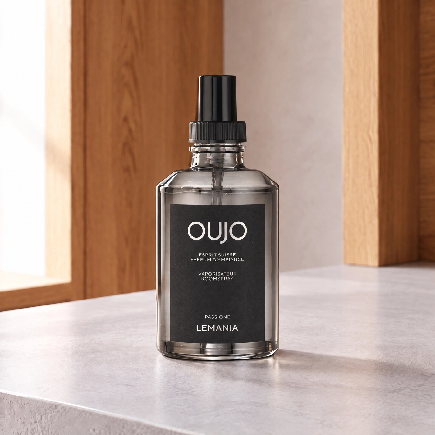 A dark bottle of room spray named OUJO on a light surface.