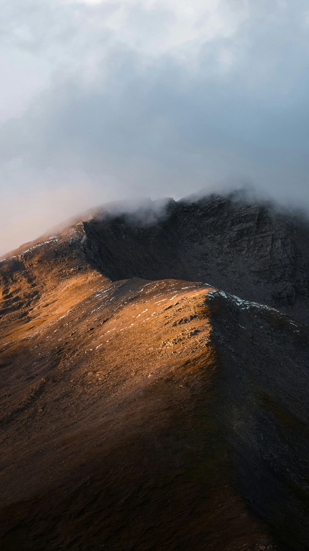 Mountain ridge in golden light with clouds.