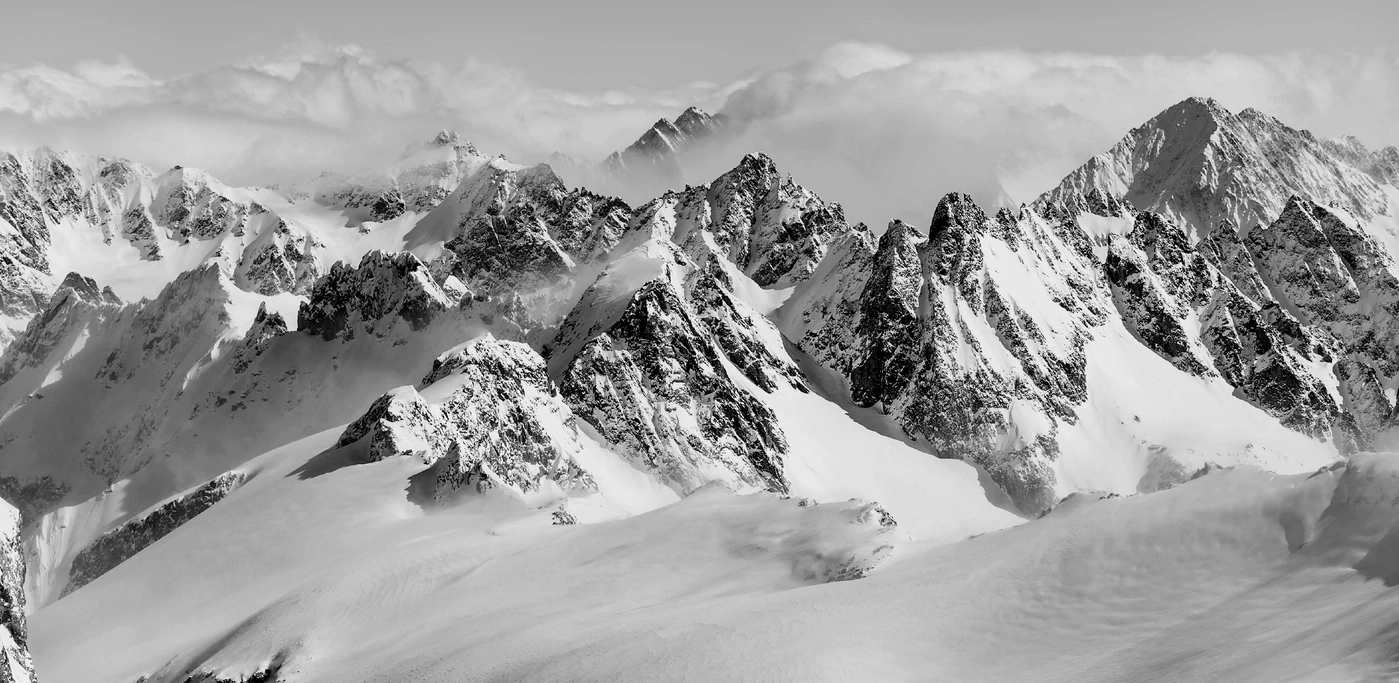 Snow-covered mountain peaks with clouds in the background.