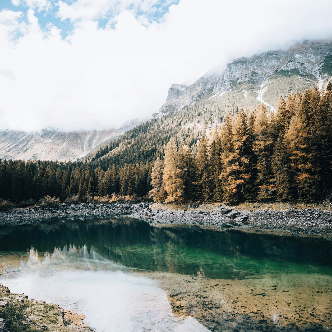 Mountain lake with golden trees and reflection in the water.