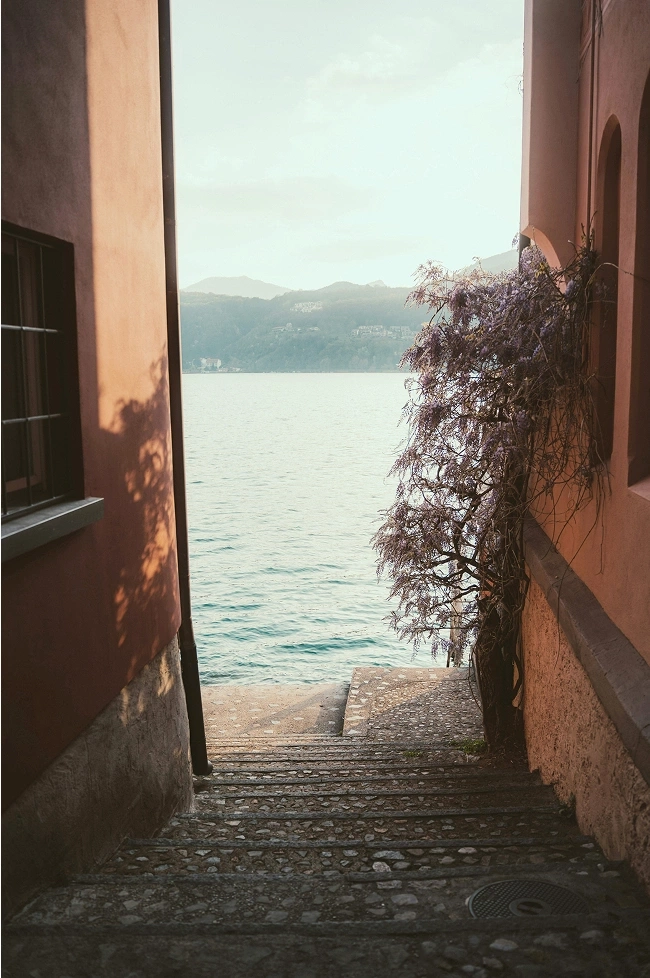 Stone steps descend to a serene lake with treed hills in the distance.
